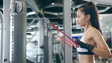 年轻的亚洲女士在健身课上做运动机械电缆交叉体脂燃烧锻炼。运动员六包，女运动员娱乐活动，功能性训练，健康的生活方式.